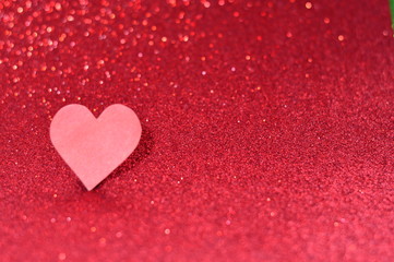 Red paper heart on a red shiny background.