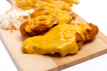 A close up of cheesy chicken breast set with fries and coleslaw insight 