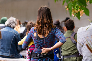 Closeup rear view of woman putting mobile phone in belt and listening fairytale story with audience in background at world and spoken word festival