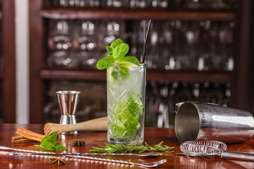 mojito cocktail on a wooden stand and bar acsessoires: shaker