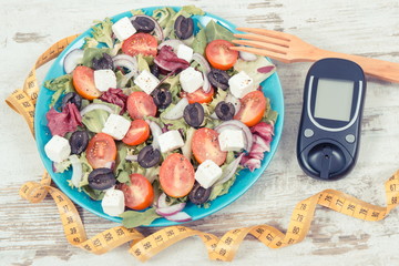 Glucometer for checking sugar level, tape measure and fresh greek salad. Diabetes and healthy...