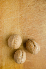 three walnuts on vintage wooden cutboard with knife marks. vertical view