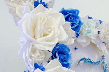 decorative ornament for the holiday of large artificial white and blue flowers on a white wall