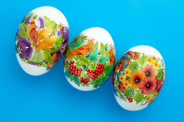 Decorated Paschal chicken eggs on blue background. Easter colored gift card.