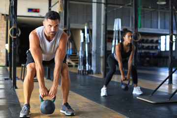 Fototapeta na wymiar Fit and muscular couple focused on lifting a dumbbell during an exercise class in a gym.