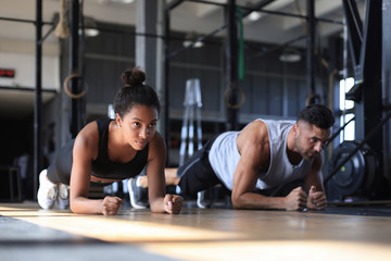 Portrait of beautiful young sports couple on a plank position.