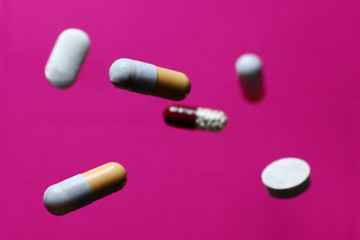 randomly scattered pills on a pink background