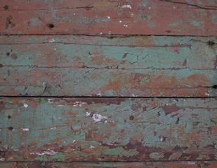 Texture. Fragment of an old wooden wall covered with cracked red, brown and green paint. Close-up.