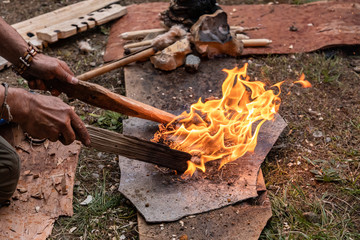 High angle view of man hand holding wooden sticks igniting flame using straw as fire starter while...