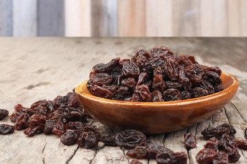 Organic dried Raisins in wood bowl on old wooden table background