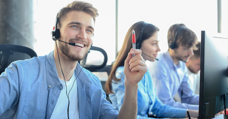 Portrait of call center worker accompanied by his team. Smiling customer support operator at work.