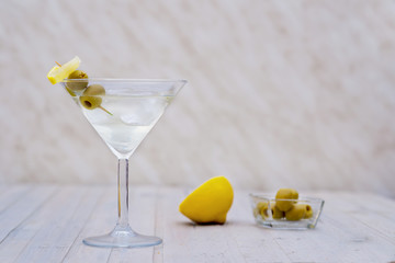 alcohol drink with ice cubes and olives in martini glass