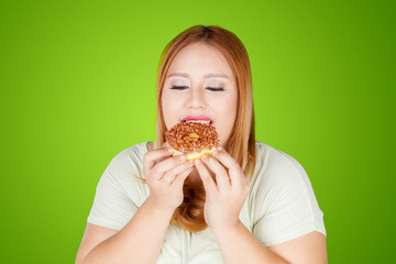 Overweight woman eating donuts in the studio