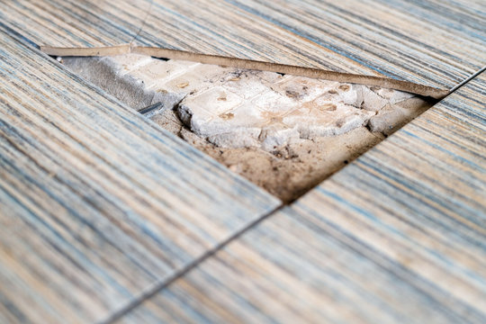 Close Up View Of Broken Tile In The Bathroom. Cracked Asbeston Floor Tile. Damaged Ceramic Tile Background