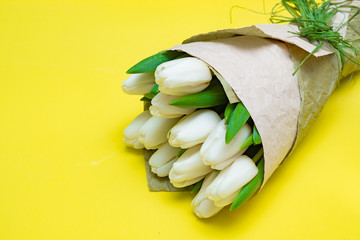 Bouquet of white tulips on a yellow background. Flat lay.