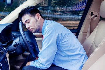 Young businessman sleeping inside his car