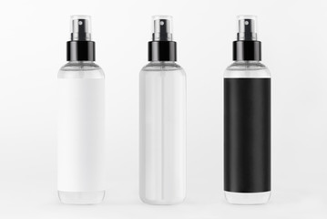 Three tall spray dispenser bottles for cosmetics  collection - transparent and with black, white label in a row on white background, mock up for design.