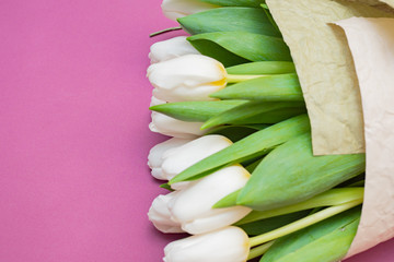 A bouquet of white tulips and a red velvet heart on a pink background-the concept of Valentine's Day.