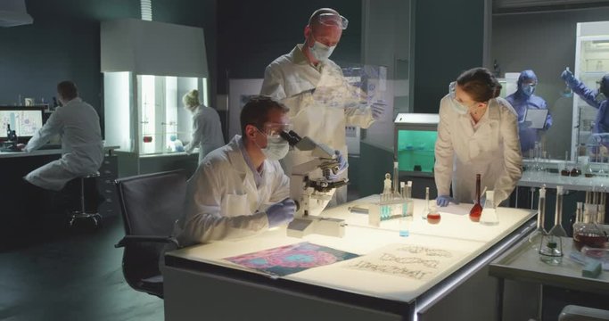 Group of scientists work on remedy or drug in modern medical laboratory. Micro biologists look for vaccine to chinese coronavirus. Clinical study of infection cure