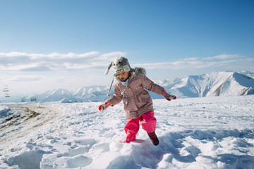 Fototapeta na wymiar Little girl walking in the snow in mountains