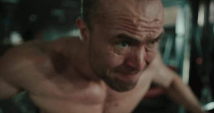Muscular bodybuilder doing cable crossover workout on machine pumping his back muscles