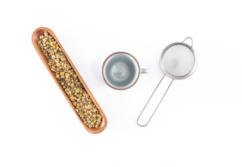 Chamomile tea with teacup and strainer or infuser - filter isolated on white background. Top view,...