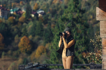 woman photographs autumn mountain landscape on DSLR camera.