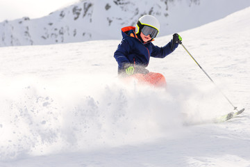 Child skiing in mountains. Ski race for young children. Abrupt ski stop with a large cloud of snow...