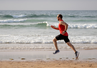 Fitness athlete runner man running and training in sport wear on the beach