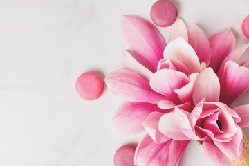 Beautiful spring pink magnolia flowers with macaroons on white table with copy space for your text. top view. flat lay