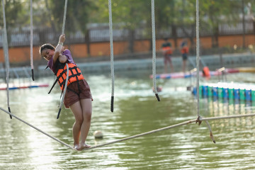 Young teenage girl walking on tight rope over the water