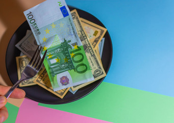 Obraz na płótnie Canvas Plate with money eat money with a fork of euros and dollars
