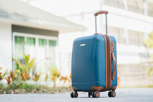 larger blue suitcase against the backdrop of the hotel lobby in the rays of sunlight. Vacation concept, summer travel.