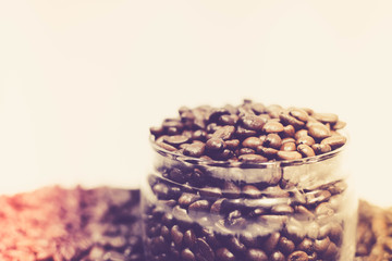 Coffee beans in a can among scattered coffee beans in a retro image