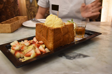 dessert with bread, ice cream, strawberries, bananas,  and honey in dish.