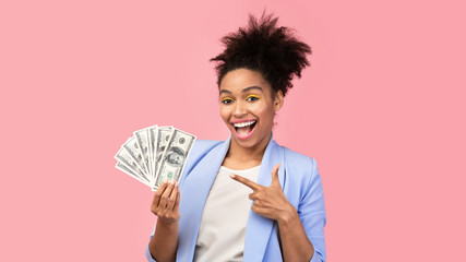 Happy black girl holding money on pink background