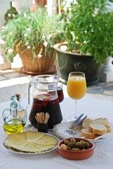A selection of tapas with a jug of Sangria and orange juice, Sliced Manchego cheese, and green...