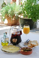 A selection of tapas with a jug of Sangria and orange juice, Sliced Manchego cheese, and green olive cocktail, Spain.