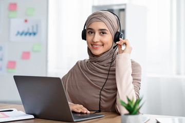 Beautiful arabic woman in hijab wearing headset working in modern office