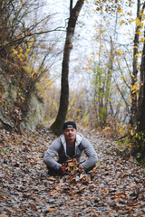 Man throwing autumn leaves in air