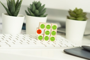 Toxic person or employee concept with different smiley faces on wooden cubes