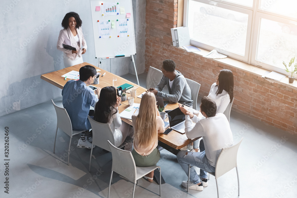 Wall mural african young woman making marketing report in front of colleagues