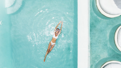 Woman relaxing in clear pool water in hot sunny day on Bali villa - obrazy, fototapety, plakaty