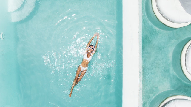 Woman relaxing in clear pool water in hot sunny day on Bali villa