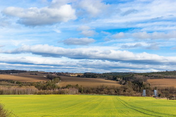 Fototapeta na wymiar Early spring landscape in South Bohemia. Green field and forest. Blue sky.