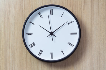 roman clock wall on woonden background. show time in late morning. black and white clock on timber...