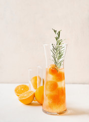 Tasty lemonade with orange juice ice cubes and rosemary in glas jug . Refreshing summer drink