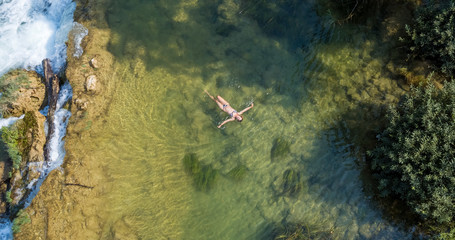 Girl floating on the waterfall on the Mreznica River, Croatia