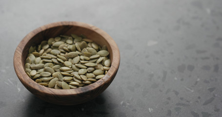 pumpkin seeds in olive bowl on terrazzo countertop with copy space