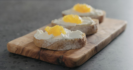 sweet bruschetta with orange marmalade and ricotta on olive board